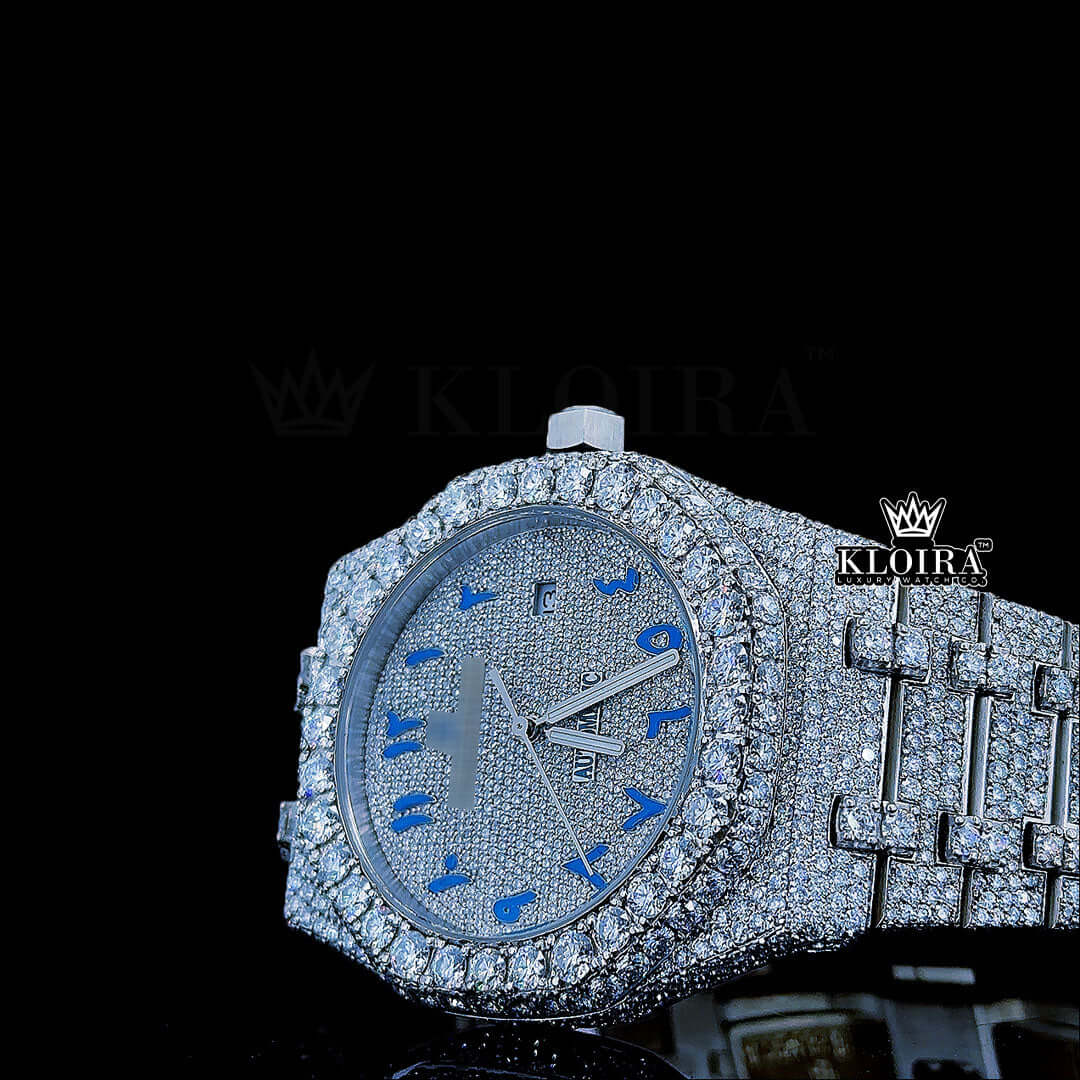 Women's AP fully iced out moissanite watch with blue Arabic dial and diamond-studded strap.
